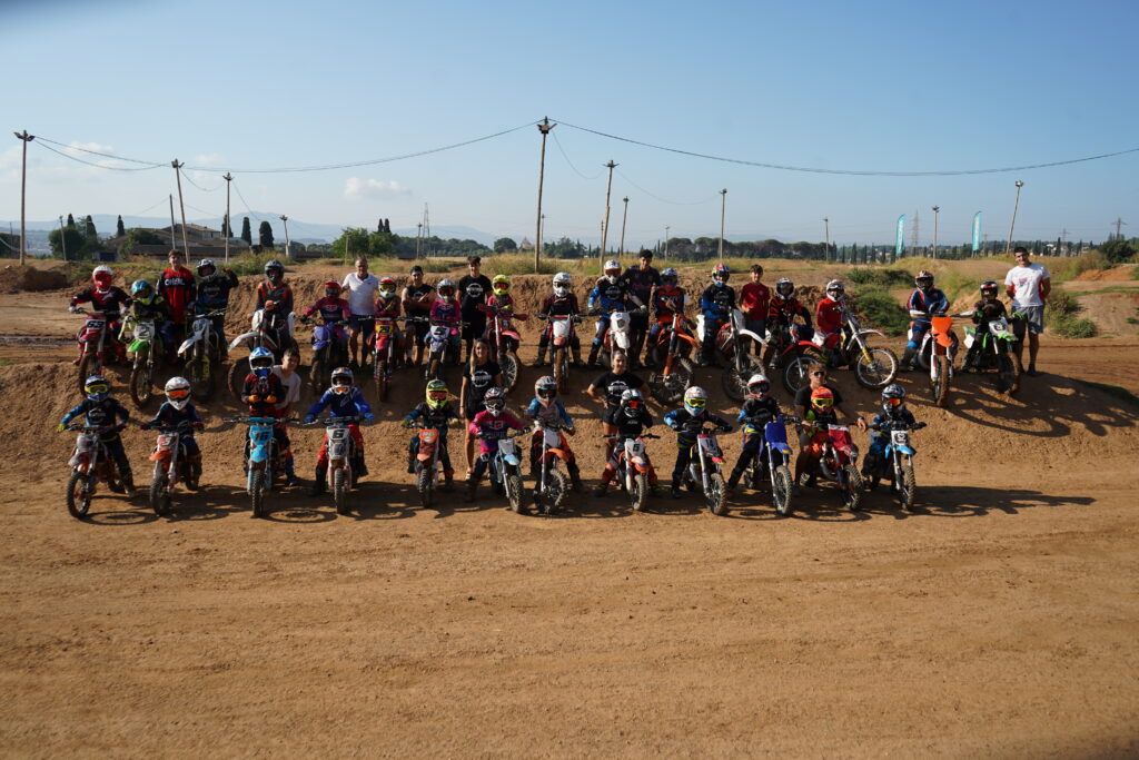 Foto de grupo de participantes y motos en el circuito de Motoffroad
